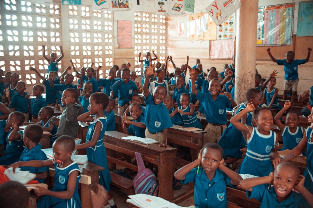 children in green uniform raising hands excitedly