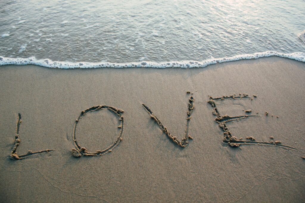 Love written on beach sand near waves at the beach